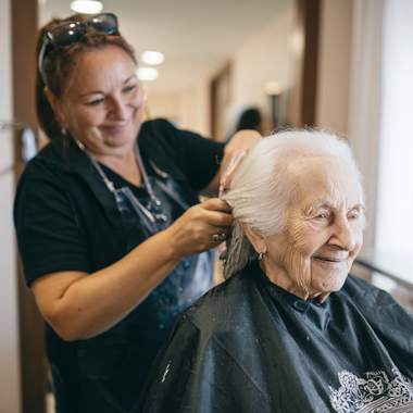 Senior patient receiving comforting bedside grooming and haircut service